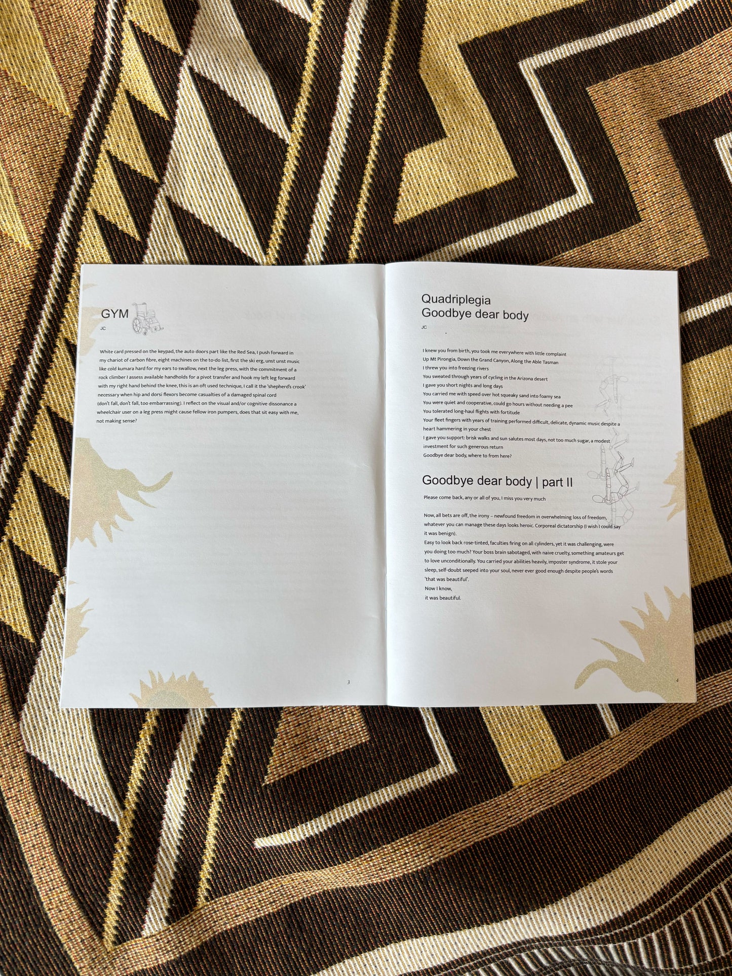 Open 'Disabled AF' zine with text on a patterned fabric. There is one poem and an illustration of a wheelchair on the left page and two poems and illustrations of wooden manikins on the right page.