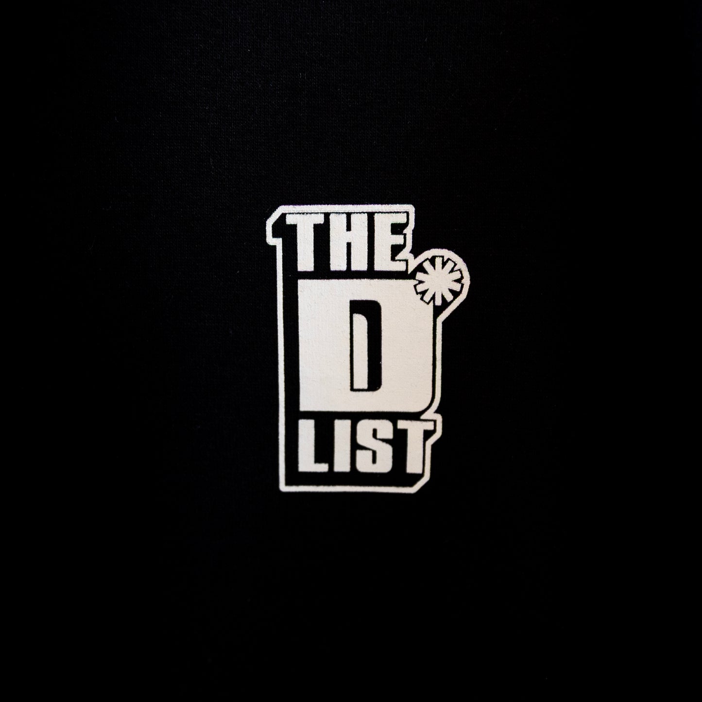 Close up of the white "The D*List" logo print on the black left chest area of the hoodie