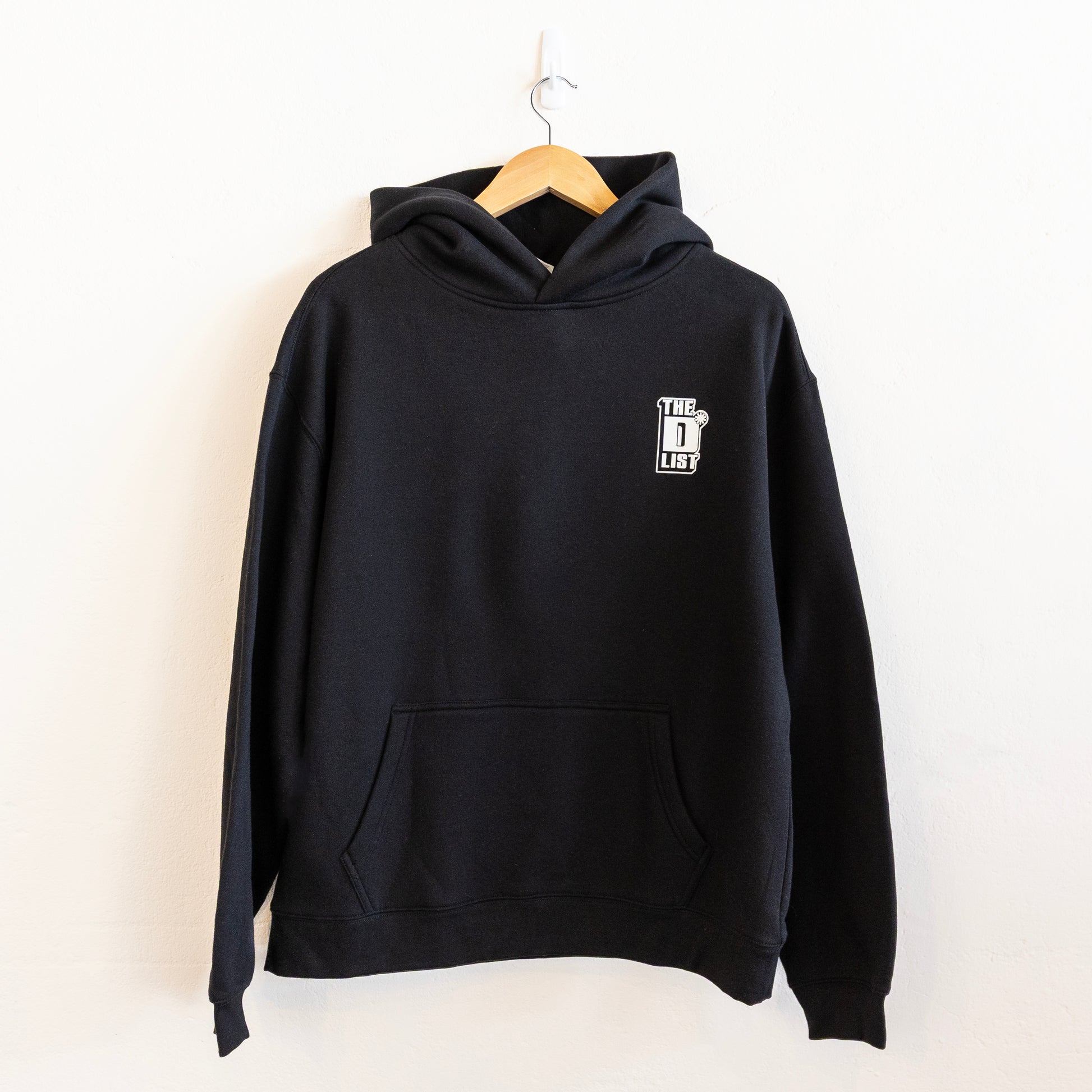 Black hoodie on a hanger against a white background. Features white "The D*List" logo on the left chest.