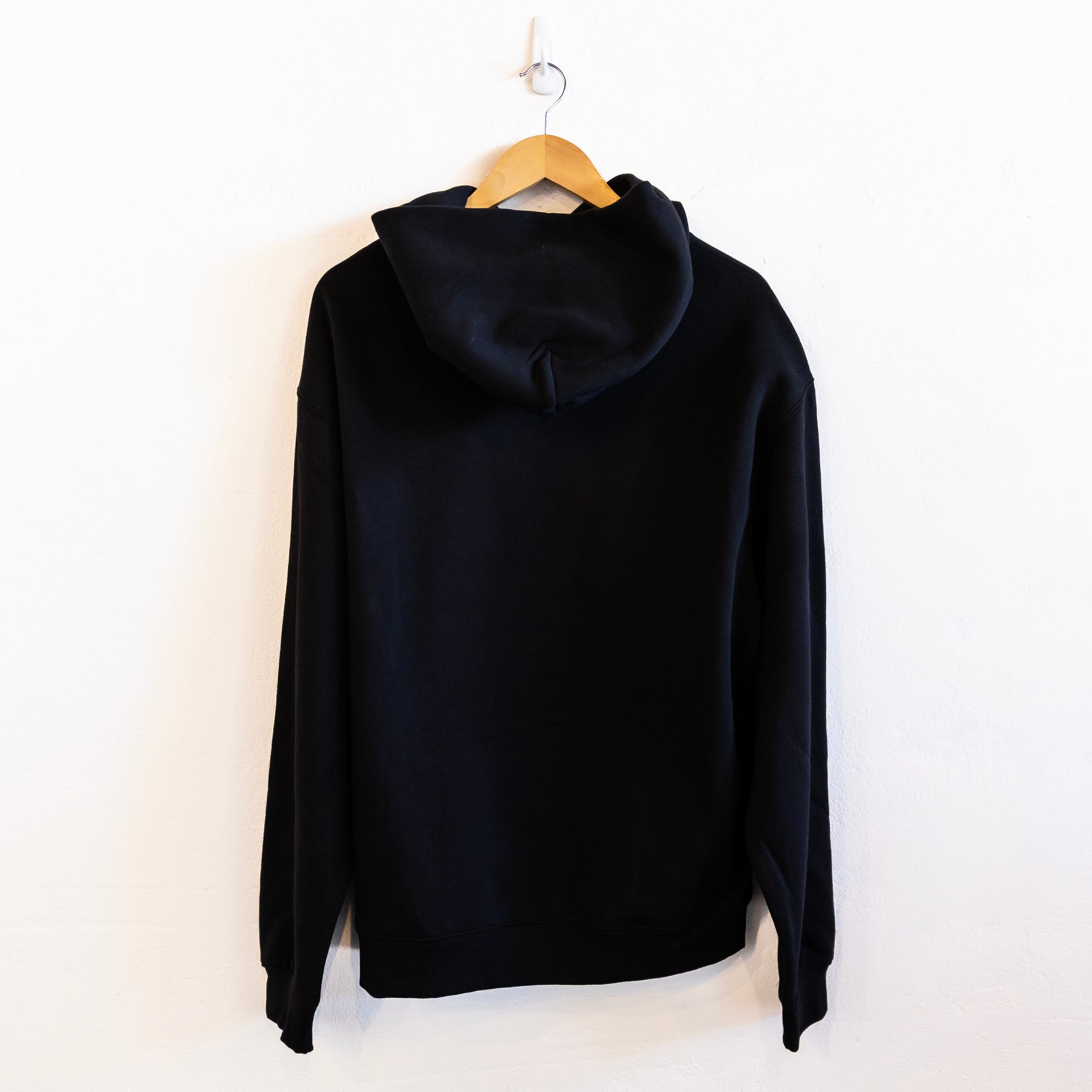 The back of a black hoodie on a hanger against a white background