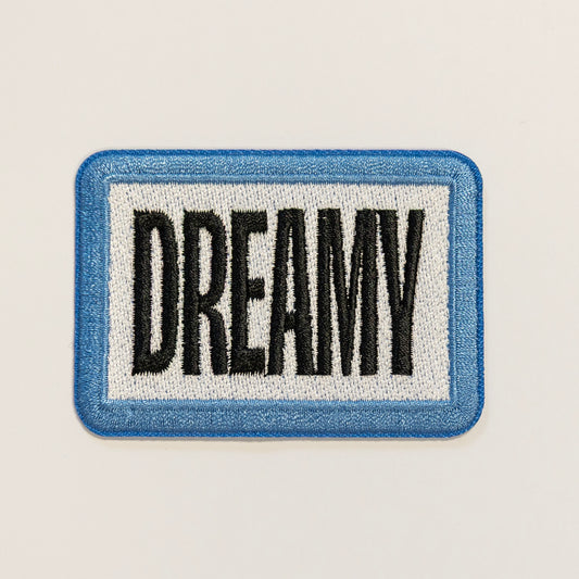 Rectangular patch with a blue border and white background, featuring the word "DREAMY" in bold black letters.