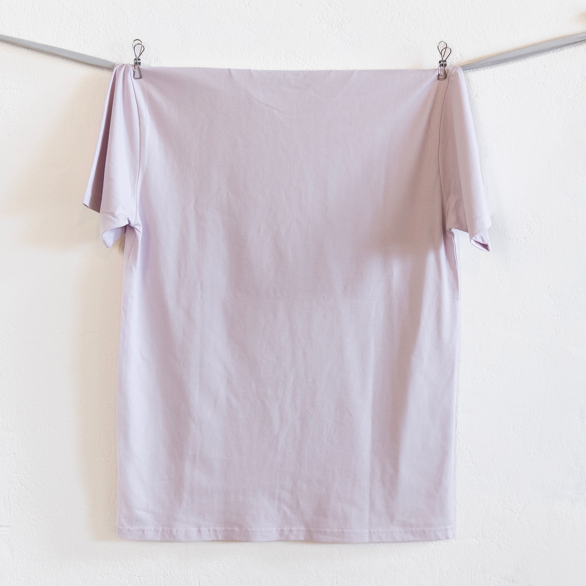 Light pink shirt hanging on a silver ribbon against a white background