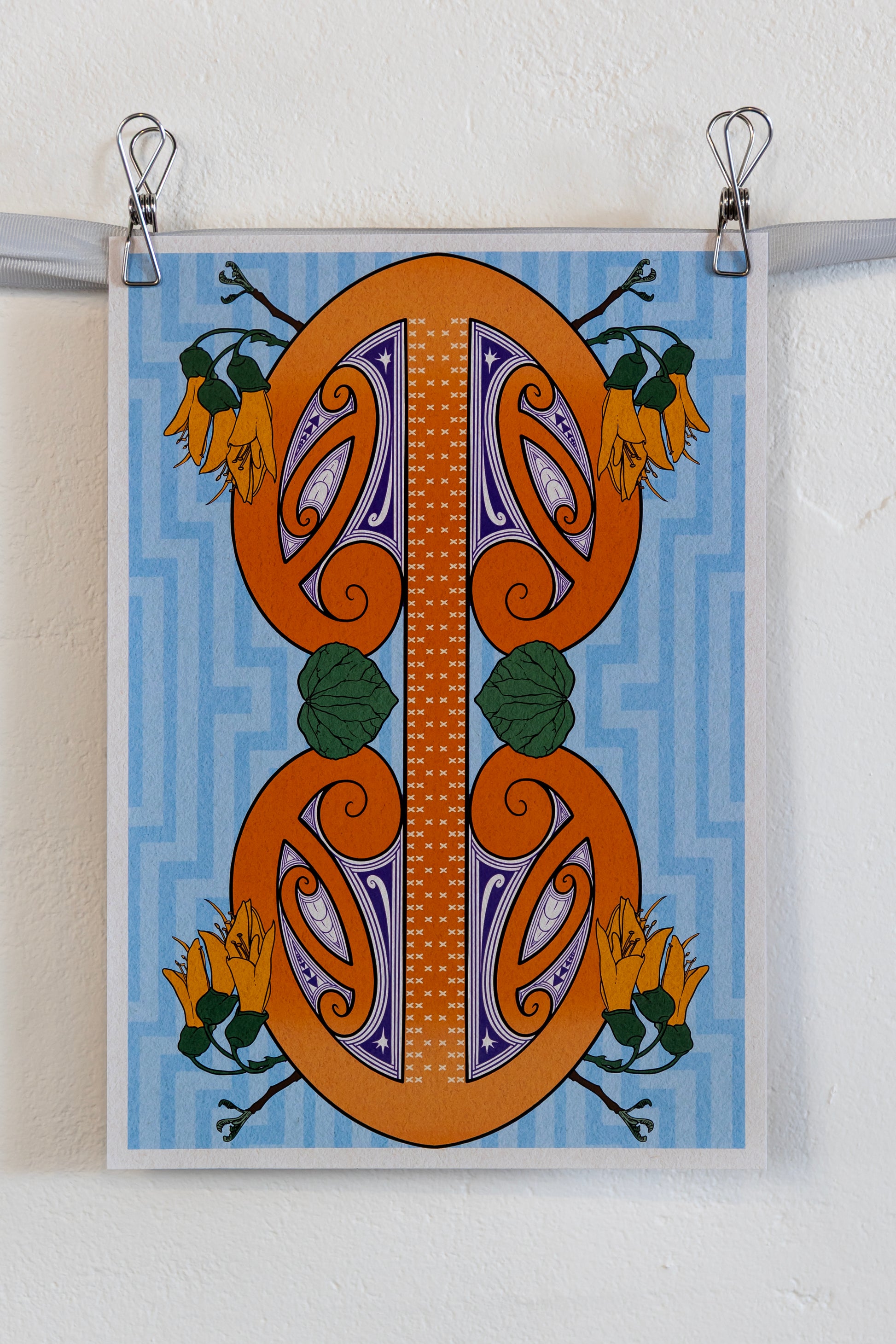 The print hung up on a silver ribbon against a white wall