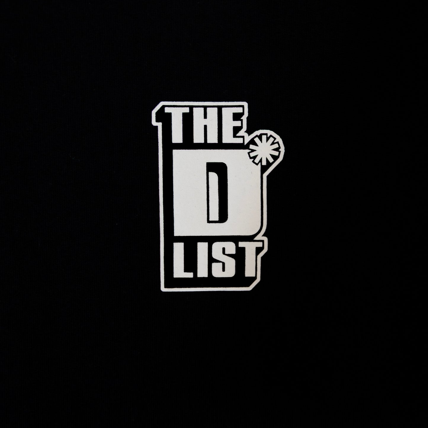 Close up of the white "The D*List" logo print on the black left chest area of the tee