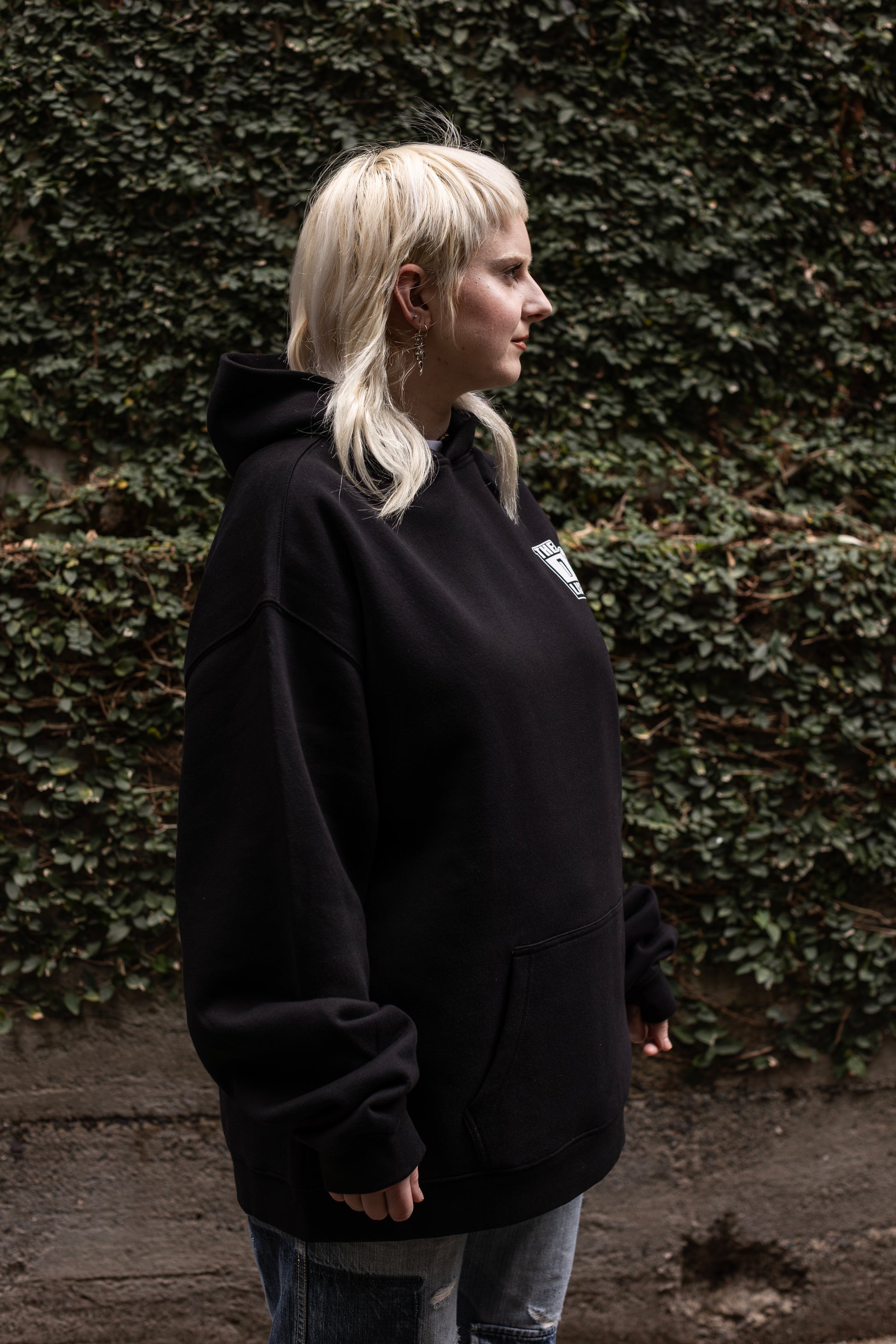 Von wearing a black hoodie white "The D*List" logo on the left chest standing against a textured wall.