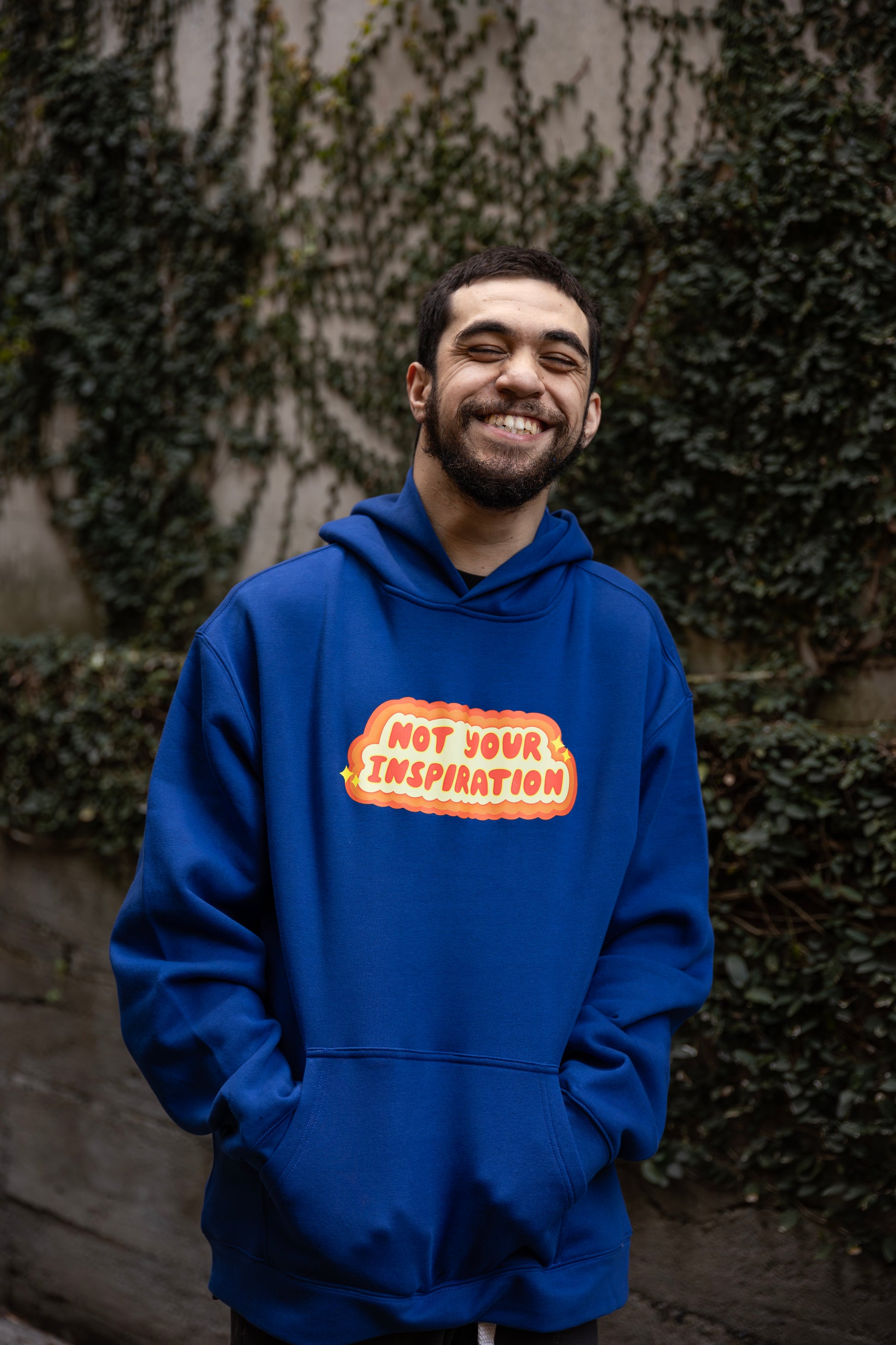 Will wearing a blue hoodie with a bold, orange and yellow text design on the front reading "Not Your Inspiration."